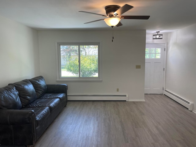 living room with ceiling fan, baseboard heating, and wood-type flooring