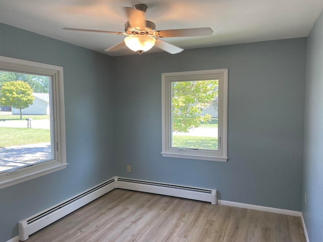 empty room featuring ceiling fan, a baseboard heating unit, and light hardwood / wood-style floors