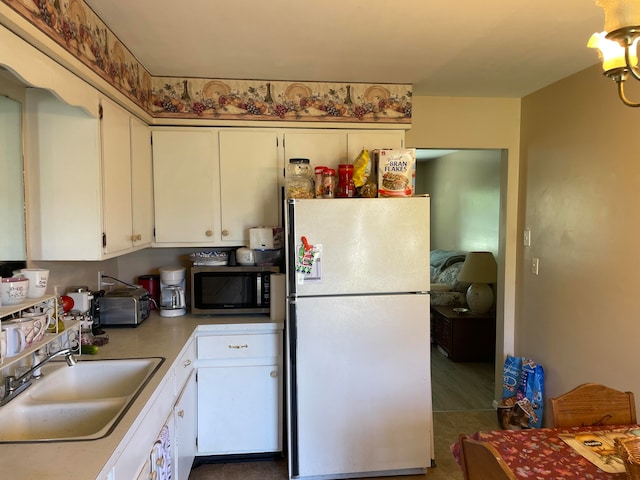 kitchen with sink, white cabinetry, dark tile patterned floors, and white fridge