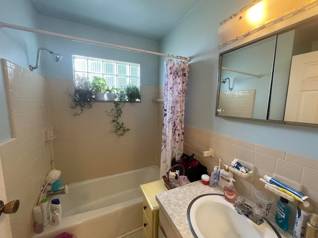 bathroom featuring backsplash, shower / bathtub combination with curtain, vanity, and tile walls