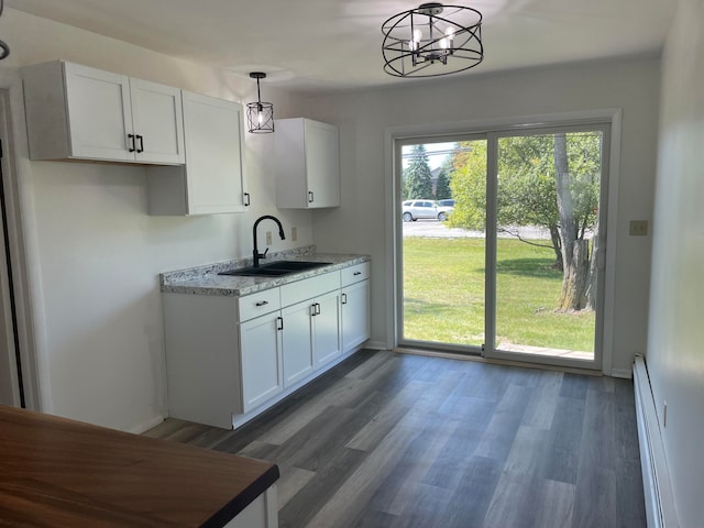 kitchen with baseboard heating, dark hardwood / wood-style floors, pendant lighting, white cabinetry, and sink