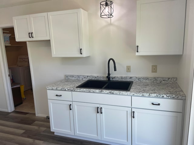 kitchen featuring white cabinetry, sink, light stone countertops, dark hardwood / wood-style flooring, and hanging light fixtures