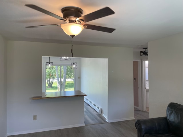 interior space featuring a baseboard radiator, ceiling fan with notable chandelier, and hardwood / wood-style floors