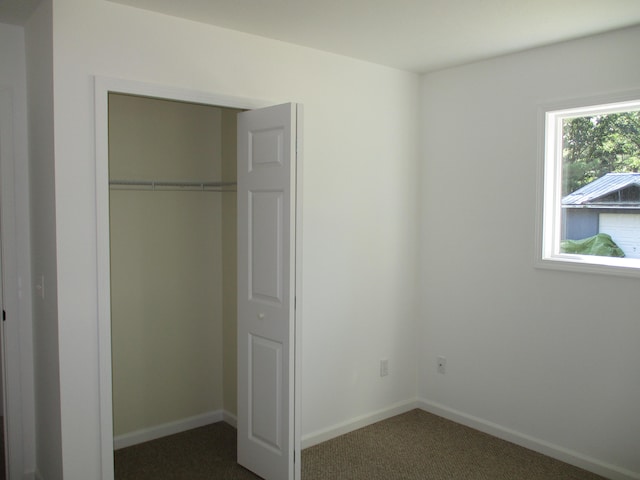 unfurnished bedroom featuring dark colored carpet and a closet