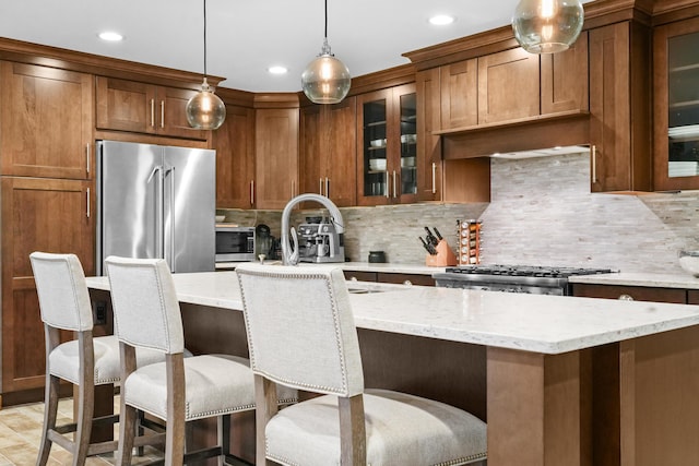 kitchen featuring tasteful backsplash, decorative light fixtures, a center island, stainless steel appliances, and light stone countertops