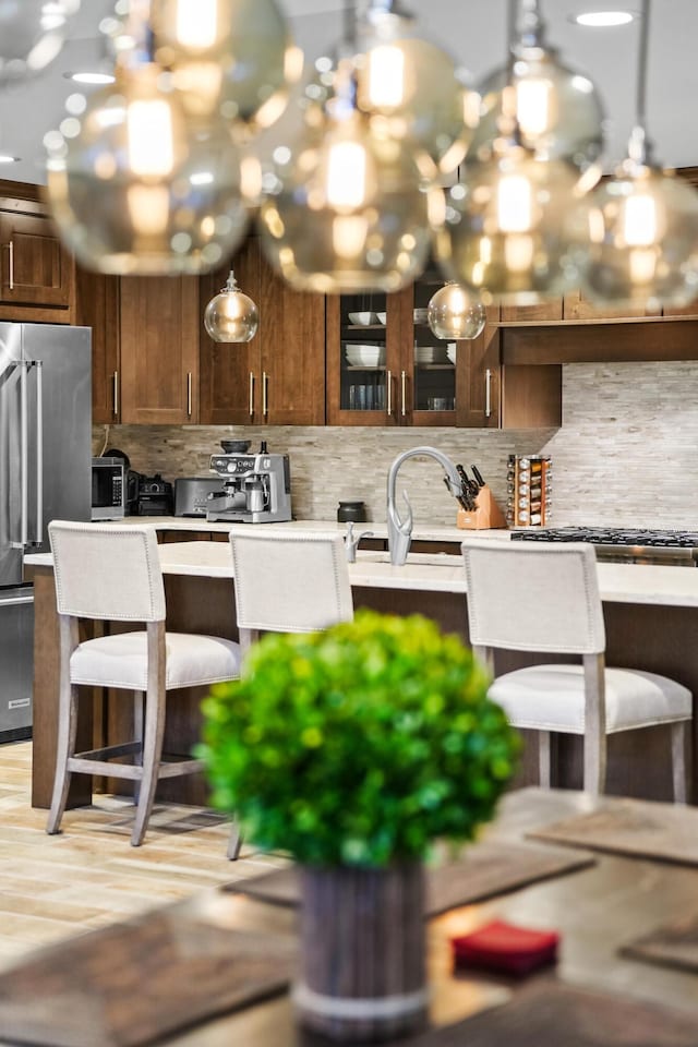 kitchen with high end fridge, sink, pendant lighting, and tasteful backsplash