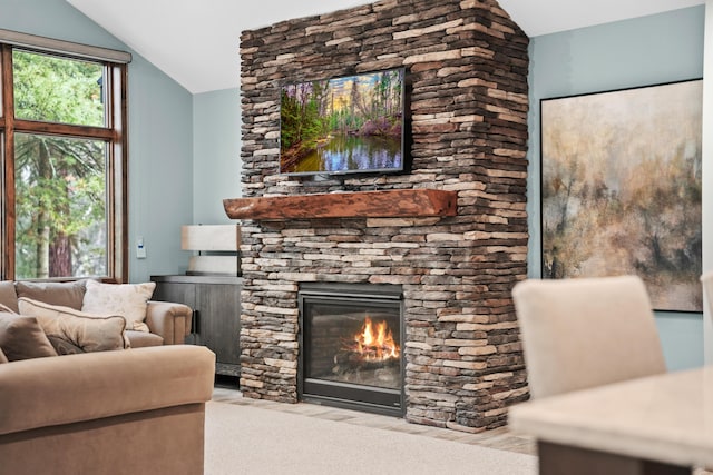 living room with lofted ceiling and a stone fireplace