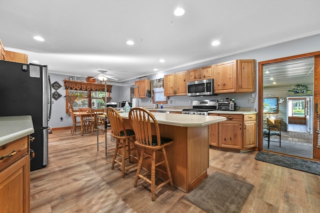 kitchen featuring light wood-type flooring, stainless steel appliances, ceiling fan, and a kitchen island