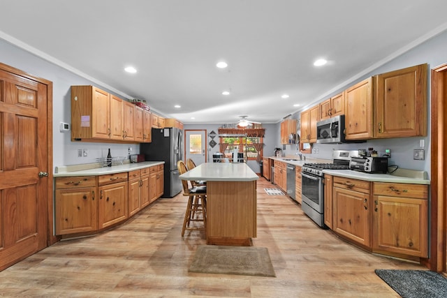 kitchen featuring light wood-type flooring, a kitchen breakfast bar, a kitchen island, appliances with stainless steel finishes, and sink