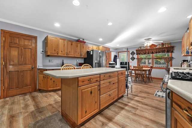 kitchen with light hardwood / wood-style floors, stainless steel appliances, ceiling fan, and a kitchen island