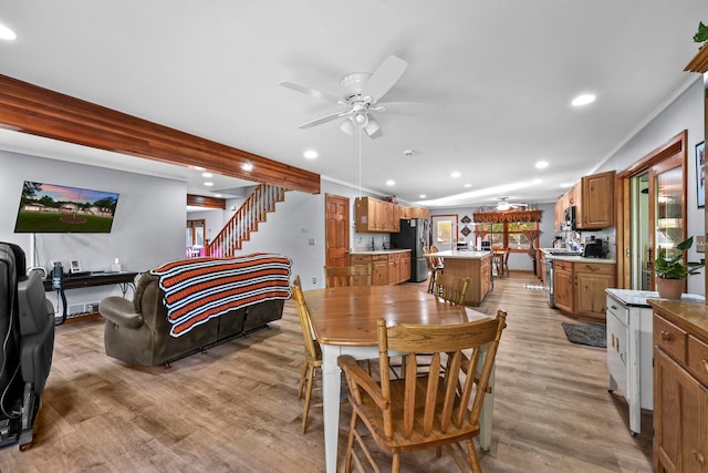 dining space featuring light wood-type flooring, ornamental molding, and ceiling fan