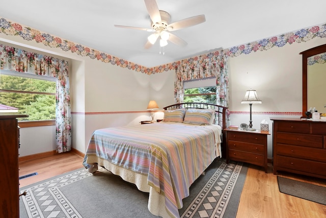 bedroom with light hardwood / wood-style flooring, ceiling fan, and multiple windows