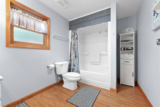 bathroom featuring hardwood / wood-style flooring, shower / bath combination with curtain, and toilet