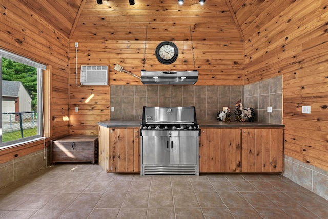 kitchen with tile patterned flooring, stainless steel range, high vaulted ceiling, wood ceiling, and a wall unit AC