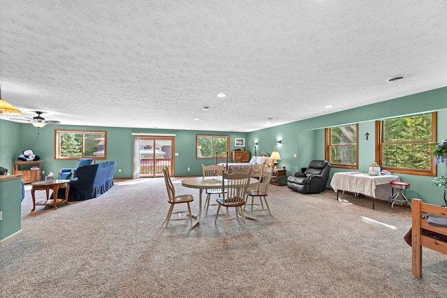 carpeted dining room with ceiling fan and a textured ceiling