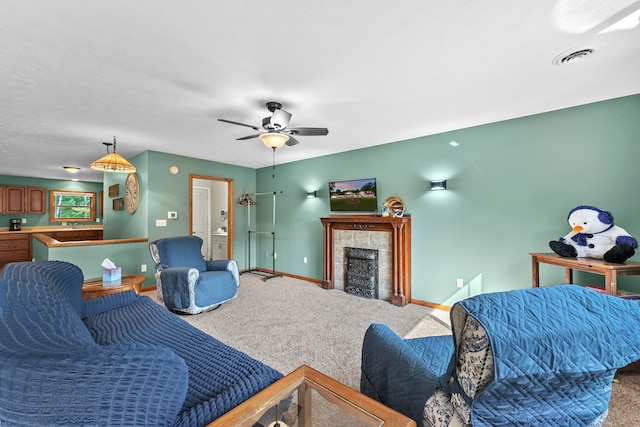 living room with ceiling fan, carpet, and a tile fireplace