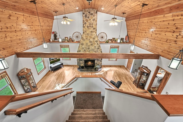 stairway featuring a fireplace, wooden walls, ceiling fan, and wood-type flooring