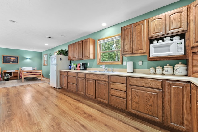 kitchen featuring light wood-type flooring, sink, and white appliances