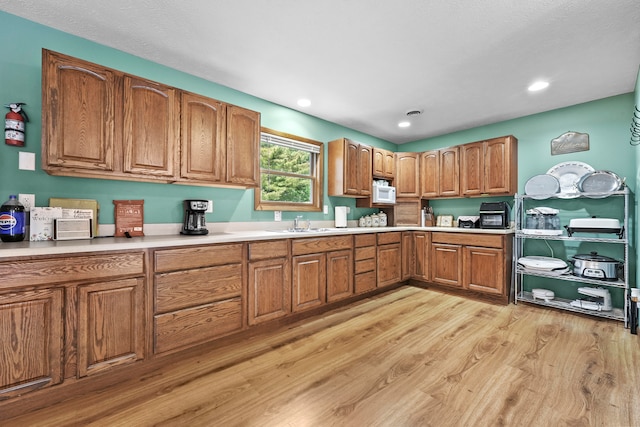 kitchen featuring sink, light hardwood / wood-style flooring, and white microwave