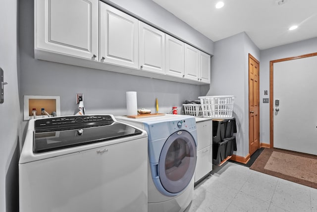 laundry room with washing machine and clothes dryer, light tile patterned floors, and cabinets