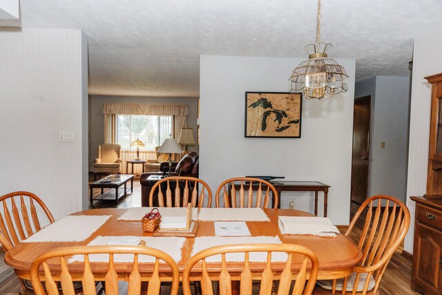 dining space with a textured ceiling, a chandelier, and wood-type flooring