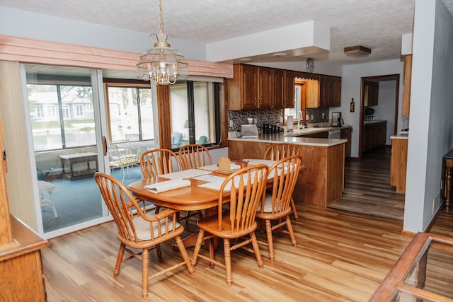 dining area with light hardwood / wood-style floors, a textured ceiling, and a chandelier