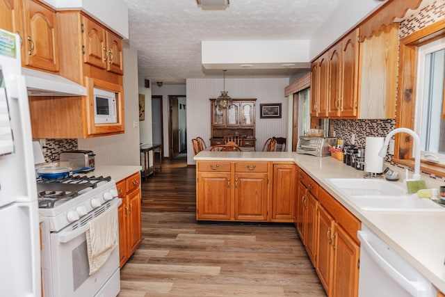 kitchen with sink, a textured ceiling, light hardwood / wood-style flooring, and white appliances