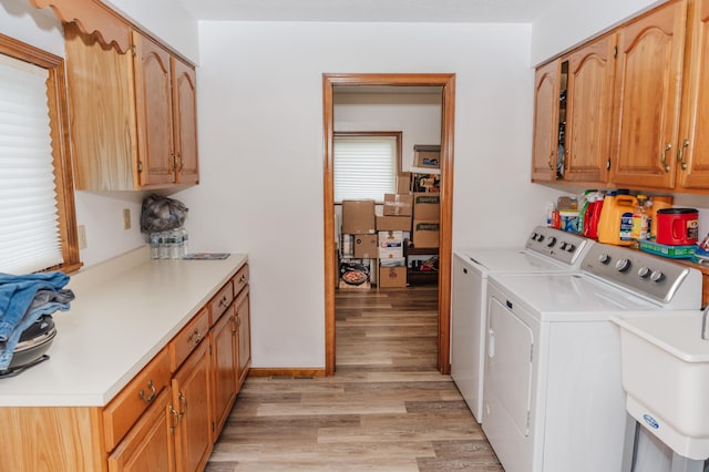 clothes washing area featuring light hardwood / wood-style floors, sink, independent washer and dryer, and cabinets