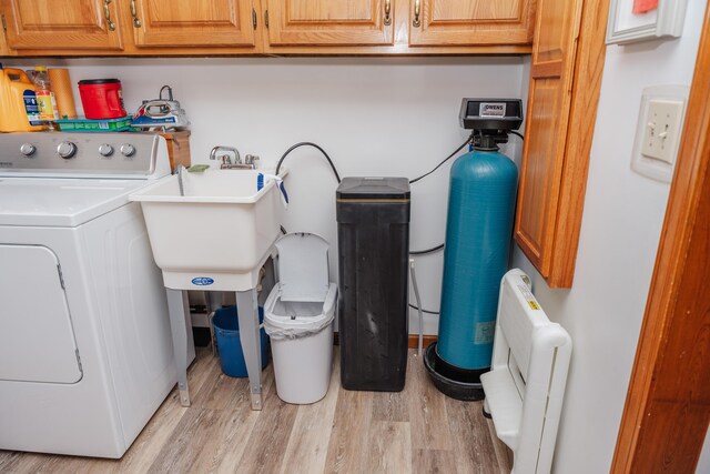 laundry room with sink, washer / dryer, light hardwood / wood-style flooring, and cabinets