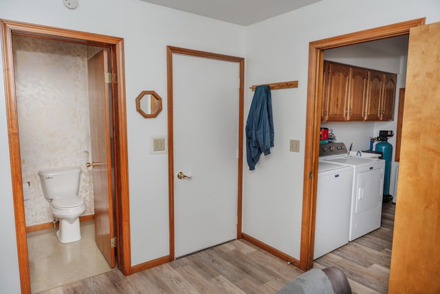 laundry area with light hardwood / wood-style flooring, cabinets, and washer and clothes dryer