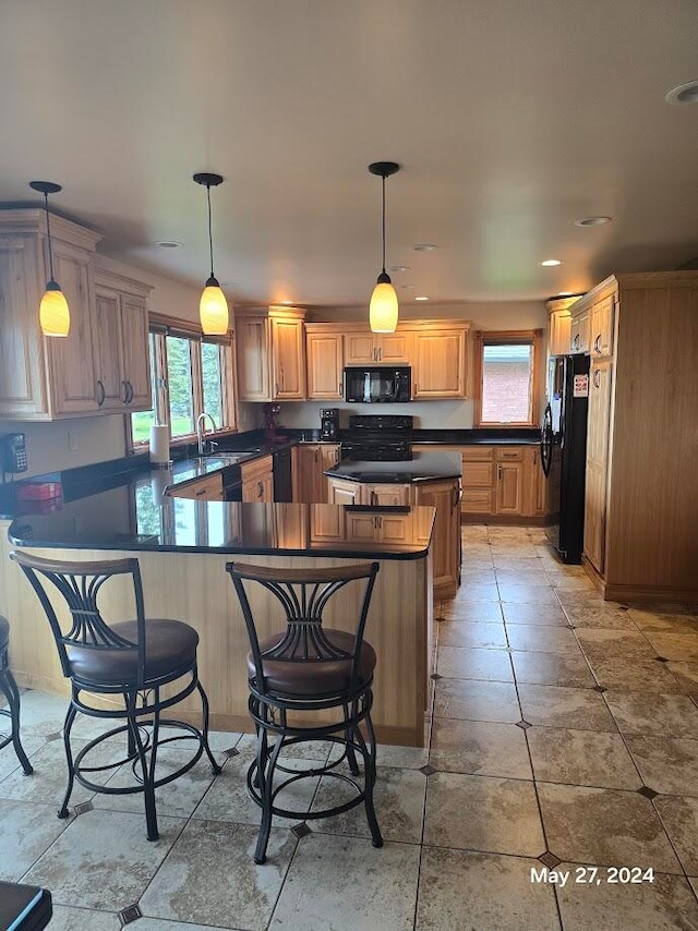 kitchen with tile patterned flooring, pendant lighting, black appliances, and kitchen peninsula