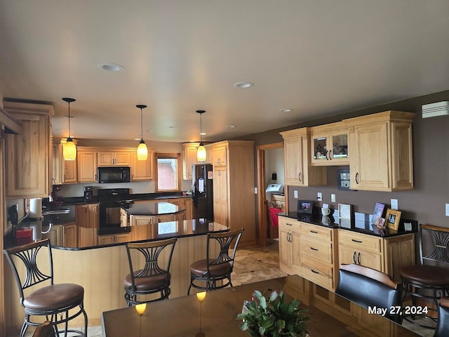 kitchen featuring a kitchen bar, sink, decorative light fixtures, tile patterned floors, and black appliances