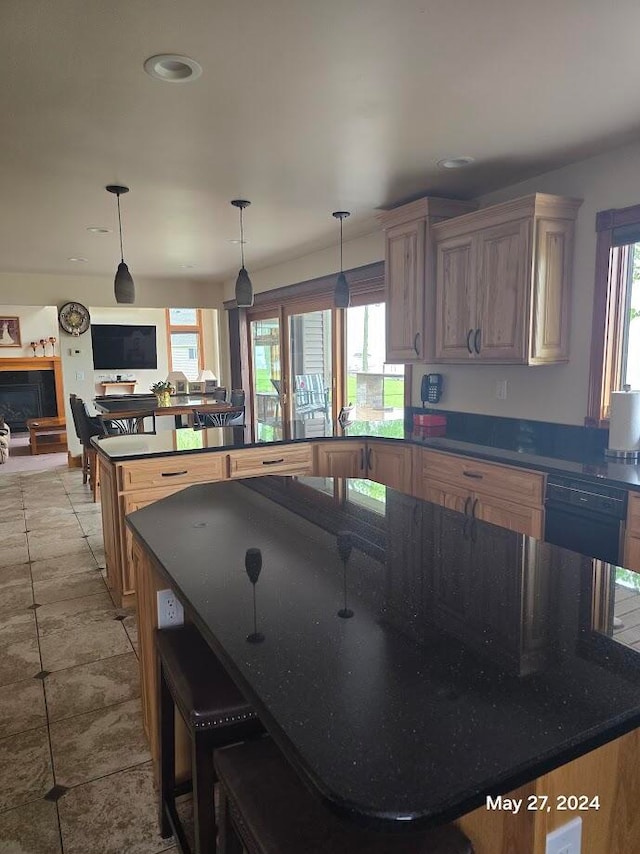 kitchen featuring black dishwasher, pendant lighting, light tile patterned flooring, and a kitchen bar