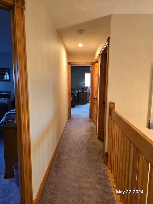 corridor with carpet flooring and a textured ceiling