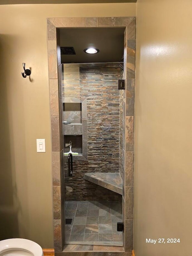 bathroom featuring a shower with door and toilet