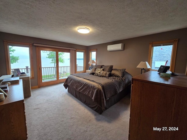 bedroom with a textured ceiling, carpet, access to outside, and a wall unit AC