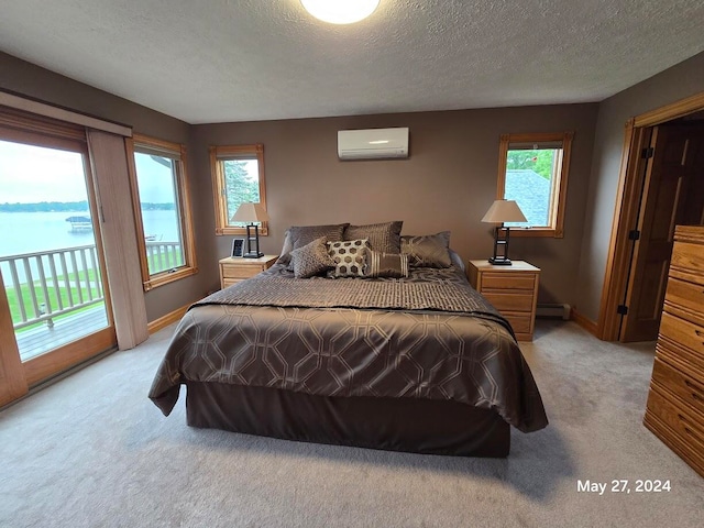 bedroom with a baseboard radiator, an AC wall unit, a textured ceiling, light colored carpet, and access to outside