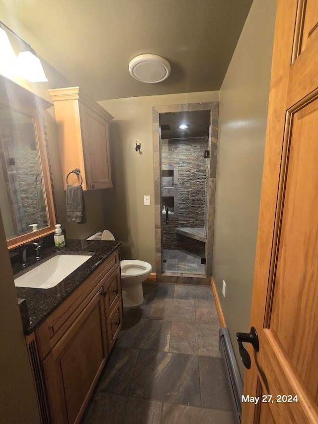 bathroom featuring baseboard heating, tile patterned flooring, vanity, toilet, and a shower with door