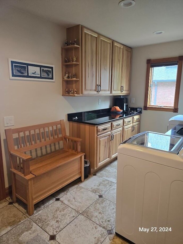 washroom featuring light tile patterned flooring, washer / clothes dryer, and cabinets