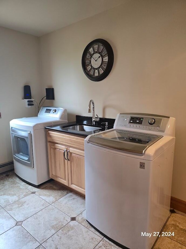 washroom with sink, washing machine and dryer, light tile patterned floors, and cabinets