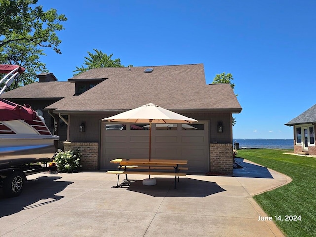 view of front facade with a water view, a garage, and a front lawn