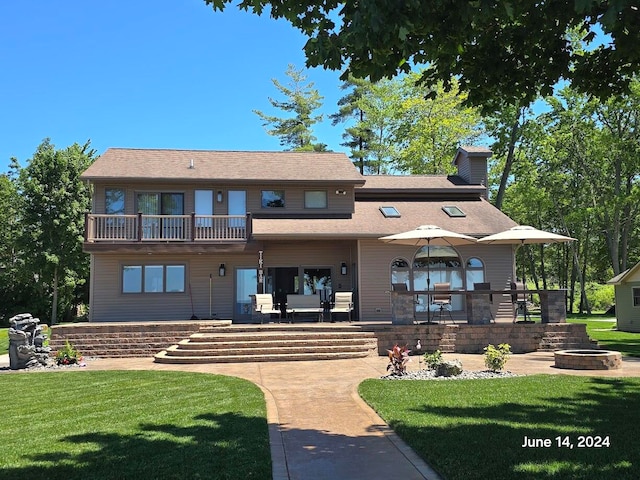 exterior space featuring a balcony, an outdoor fire pit, a patio area, and a lawn