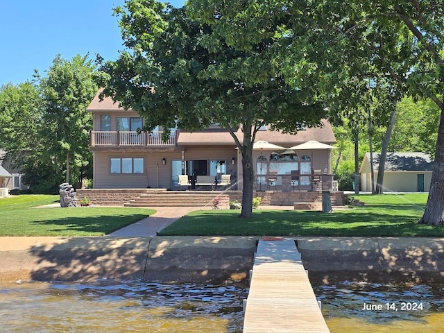 dock area featuring a balcony, a water view, and a yard