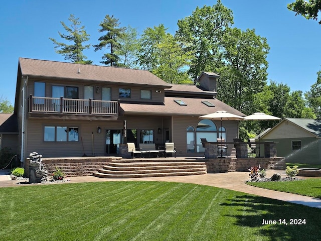 back of property with a balcony, a patio, and a yard