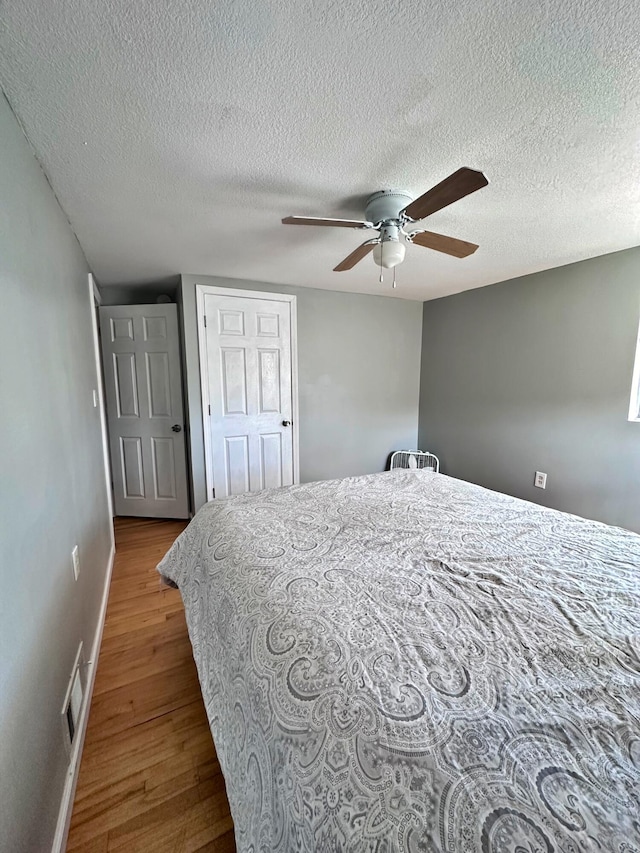 bedroom with ceiling fan, a textured ceiling, and wood-type flooring