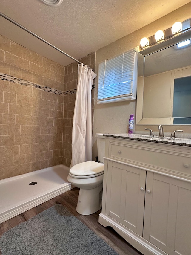 bathroom featuring toilet, vanity, hardwood / wood-style floors, curtained shower, and a textured ceiling