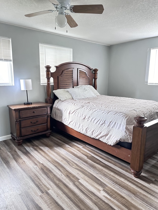 bedroom featuring ceiling fan, multiple windows, and hardwood / wood-style flooring