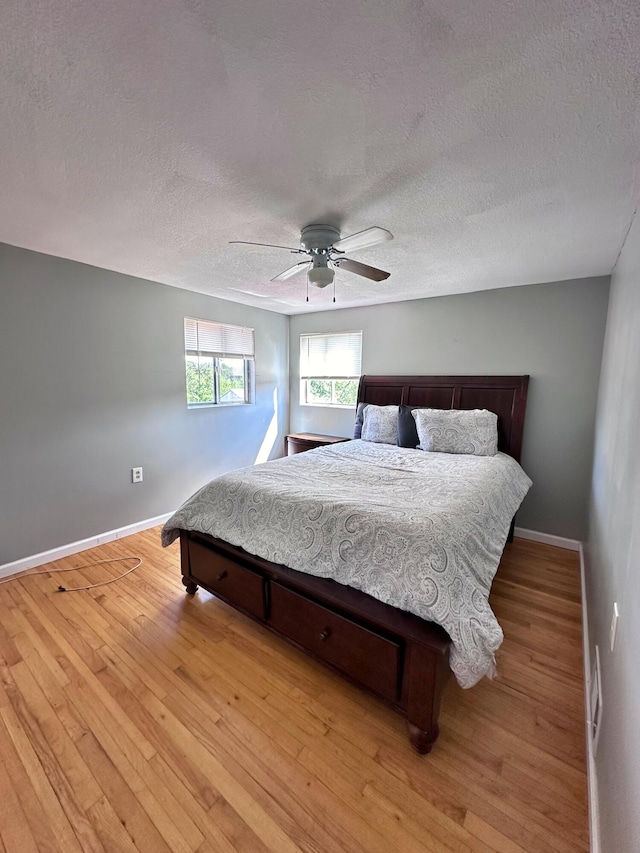 bedroom with light wood-type flooring, ceiling fan, and a textured ceiling