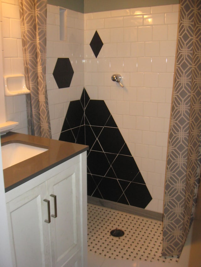 bathroom with tiled shower, tile patterned flooring, vanity, and tile walls