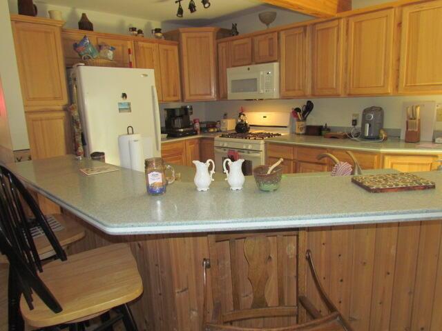 kitchen featuring white appliances, a breakfast bar area, sink, and a kitchen island with sink